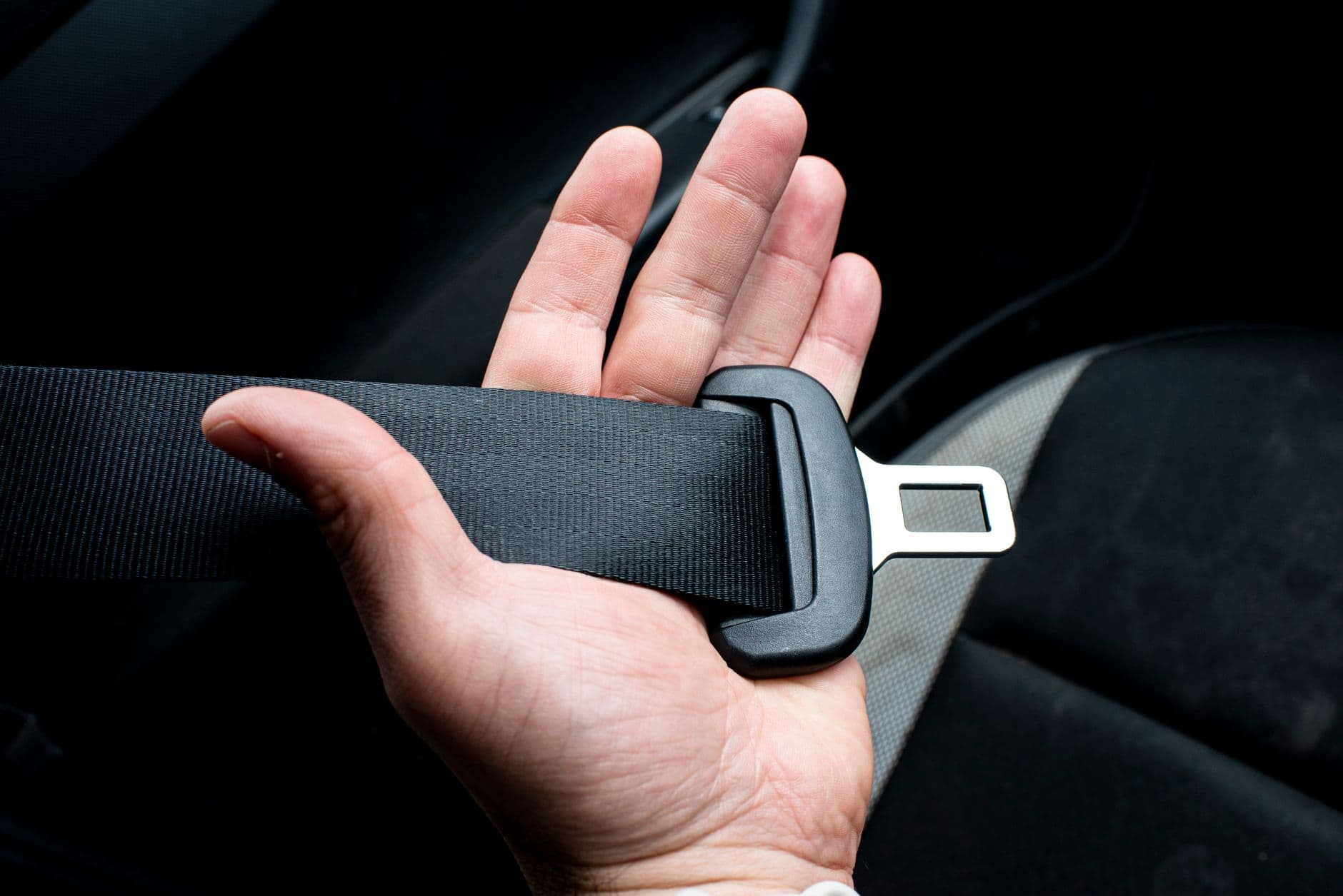 Una mano sujetando la hebilla del cinturon de seguridad de un coche