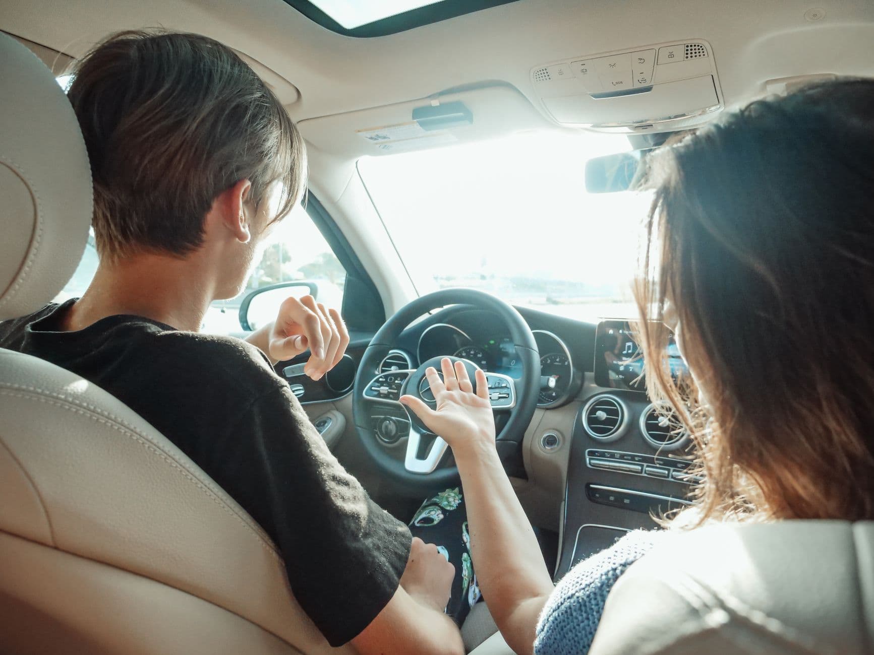 Dos personas sentadas en los asientos delanteros de un coche, vistas desde atrás