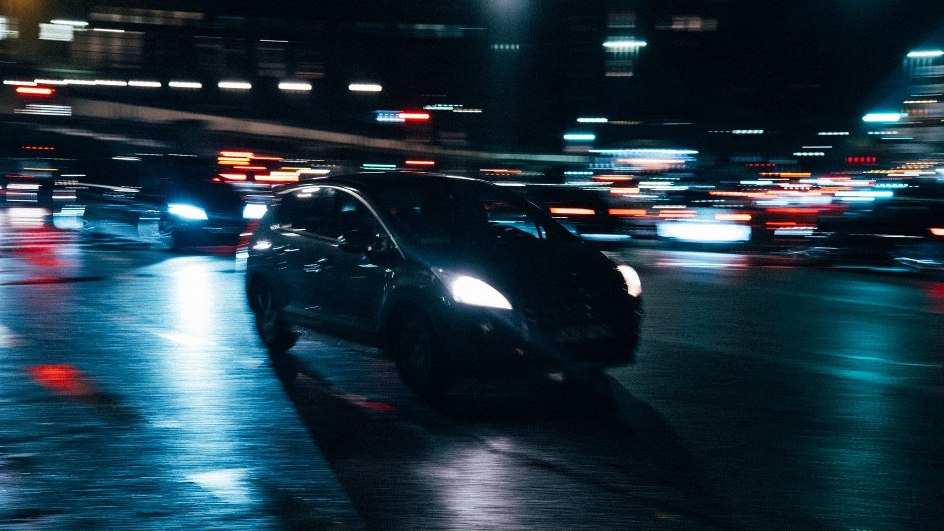 Coches circulando de noche por una avenida con las luces desenfocadas