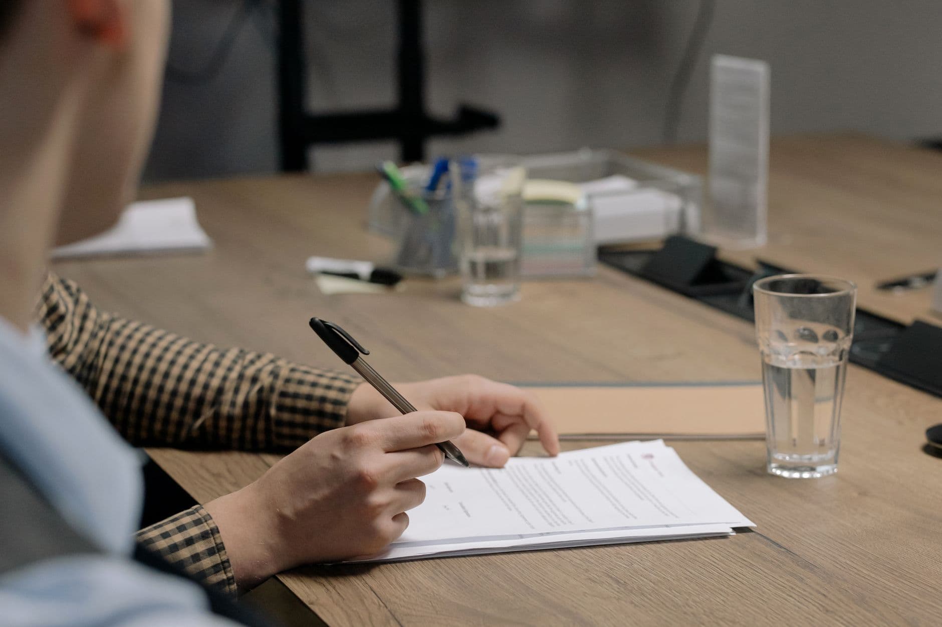 Persona firmando documentos sobre una mesa