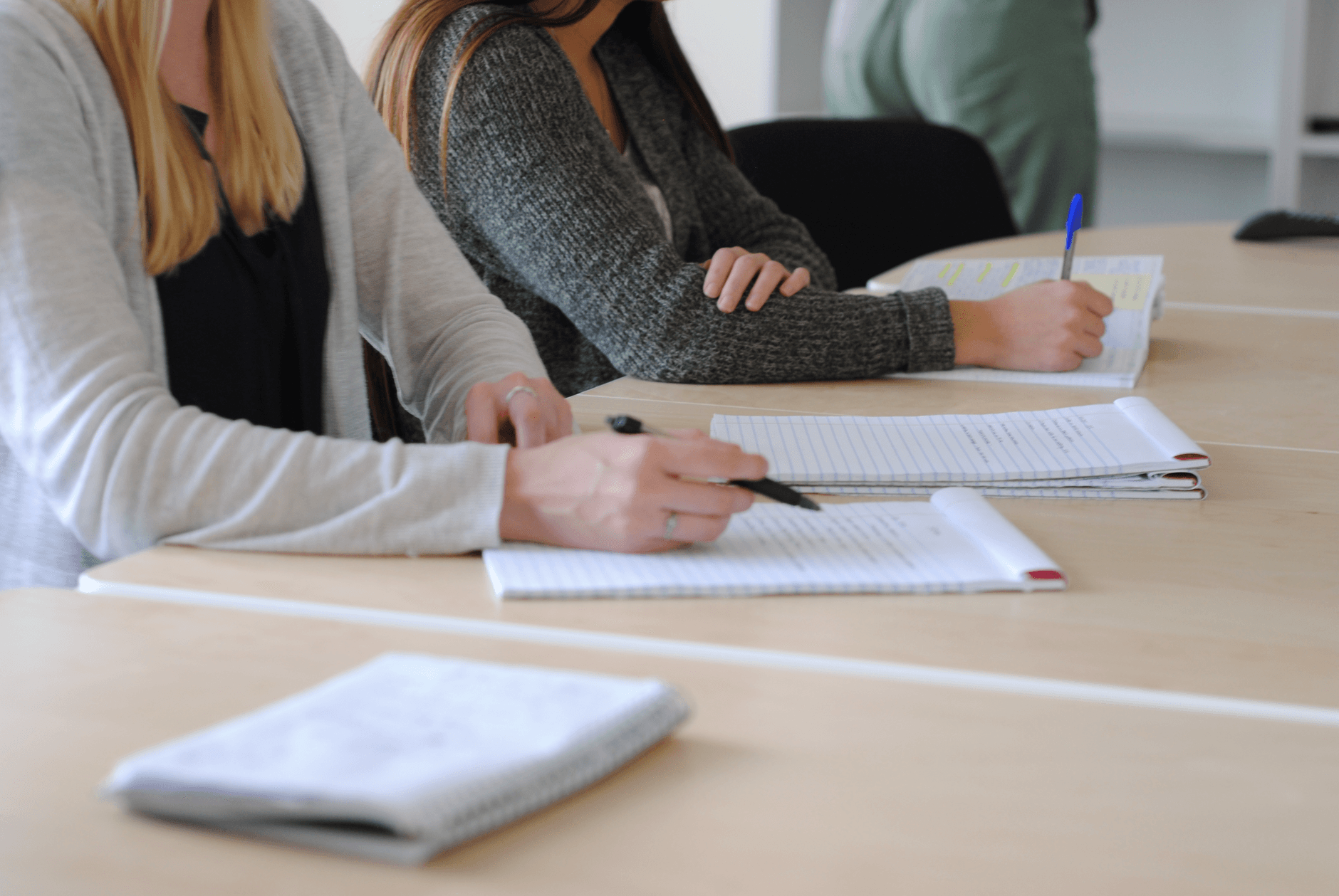 Varias personas adultas tomando notas sentadas alrededor de una mesa