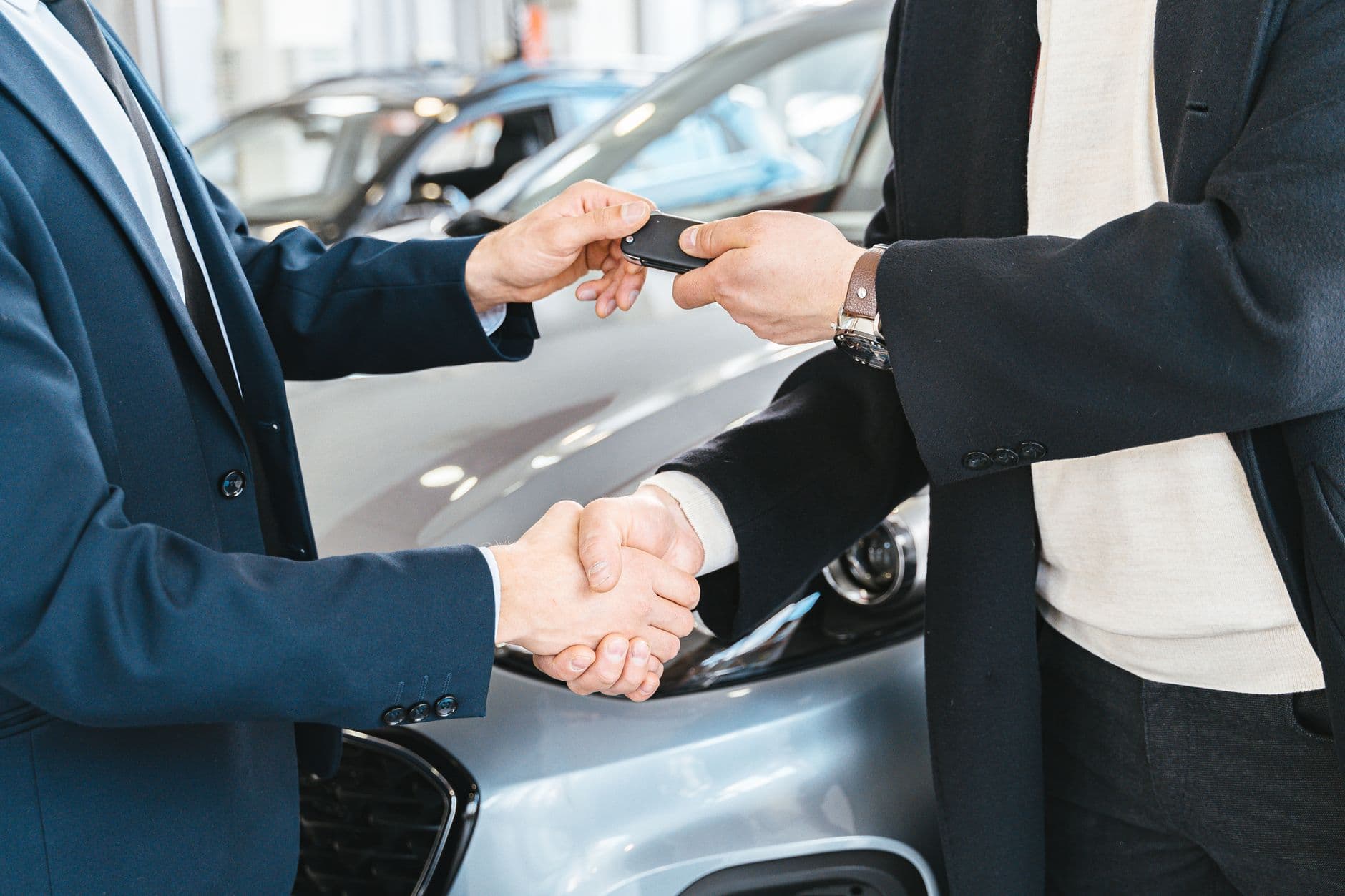 Dos personas se dan la mano mientras se entregan las llaves de un coche