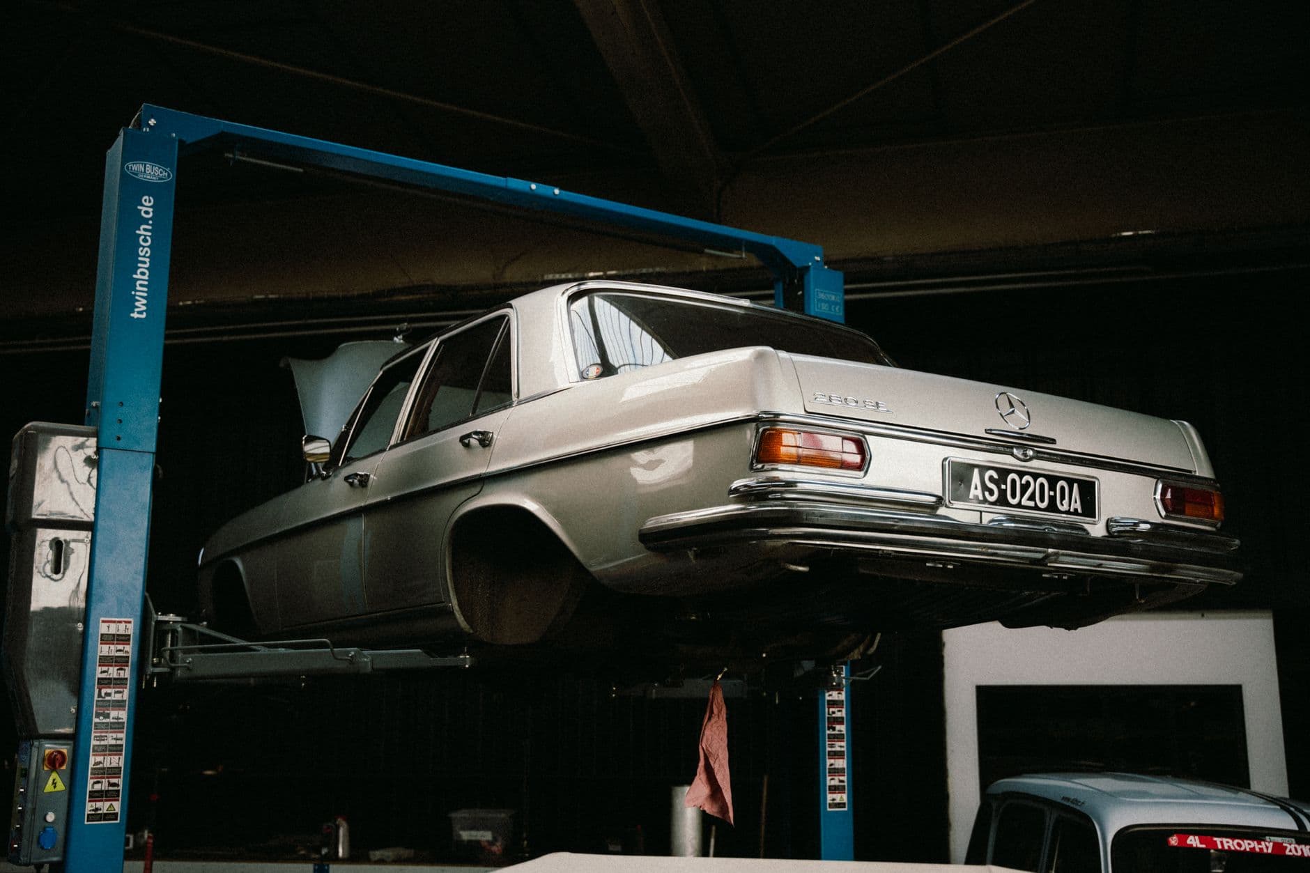 Coche clasico subido en un elevador de dos columnas en un taller